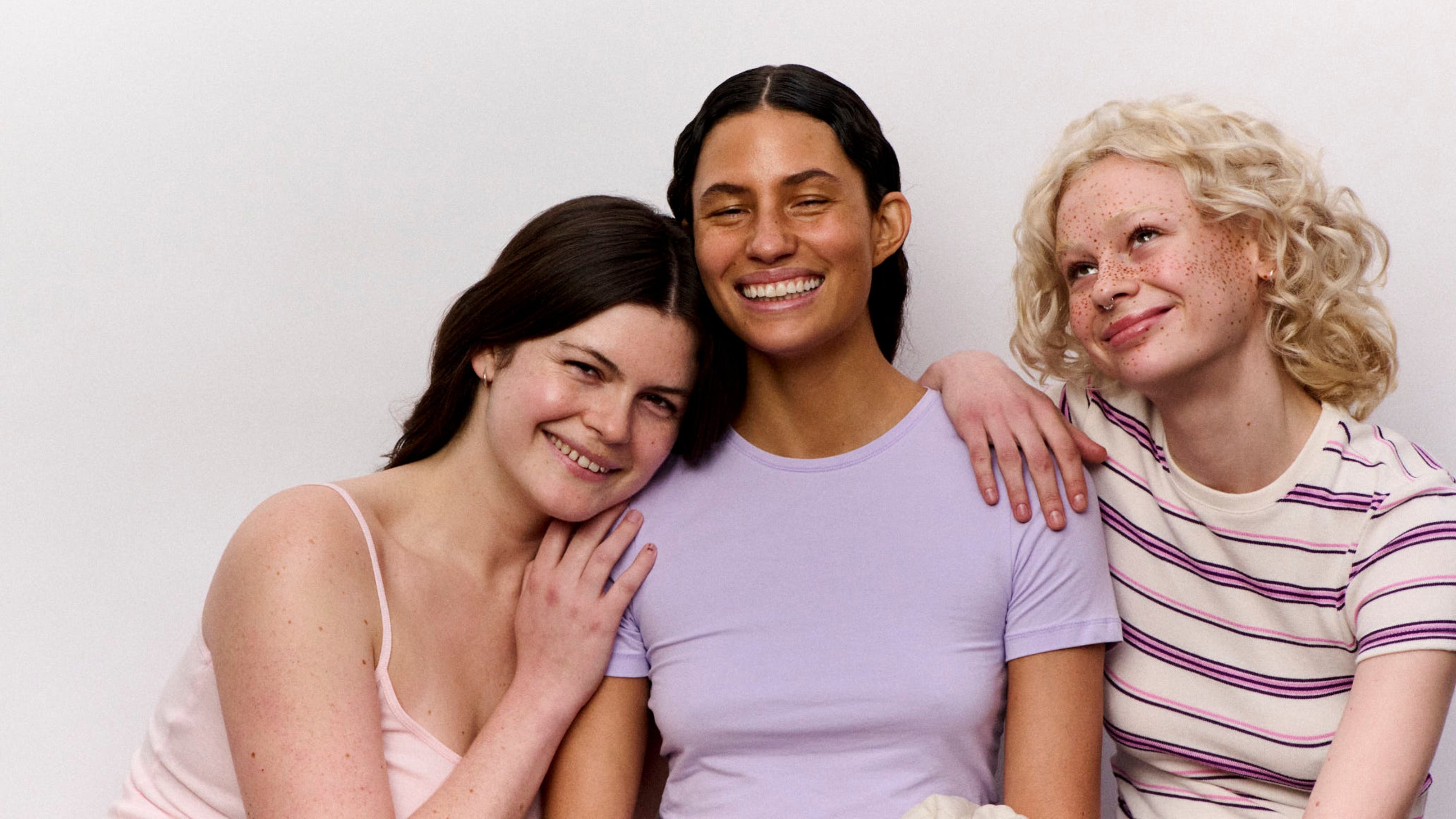 Three women posing together against a plain background