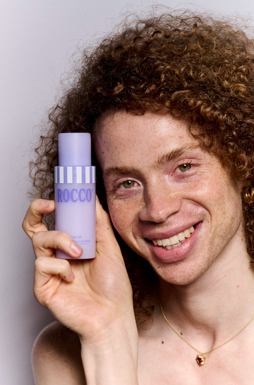 Person holding a purple bottle labeled 'Rocco' against a plain background
