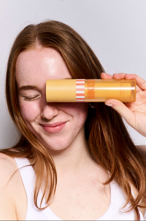 Person holding Cloud Bounce Moisturiser product in front of their face against a plain background