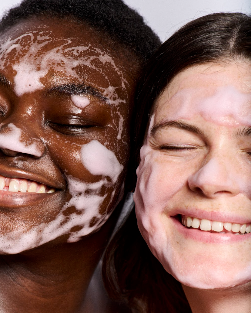 Two people with pink foam on their faces against a white background