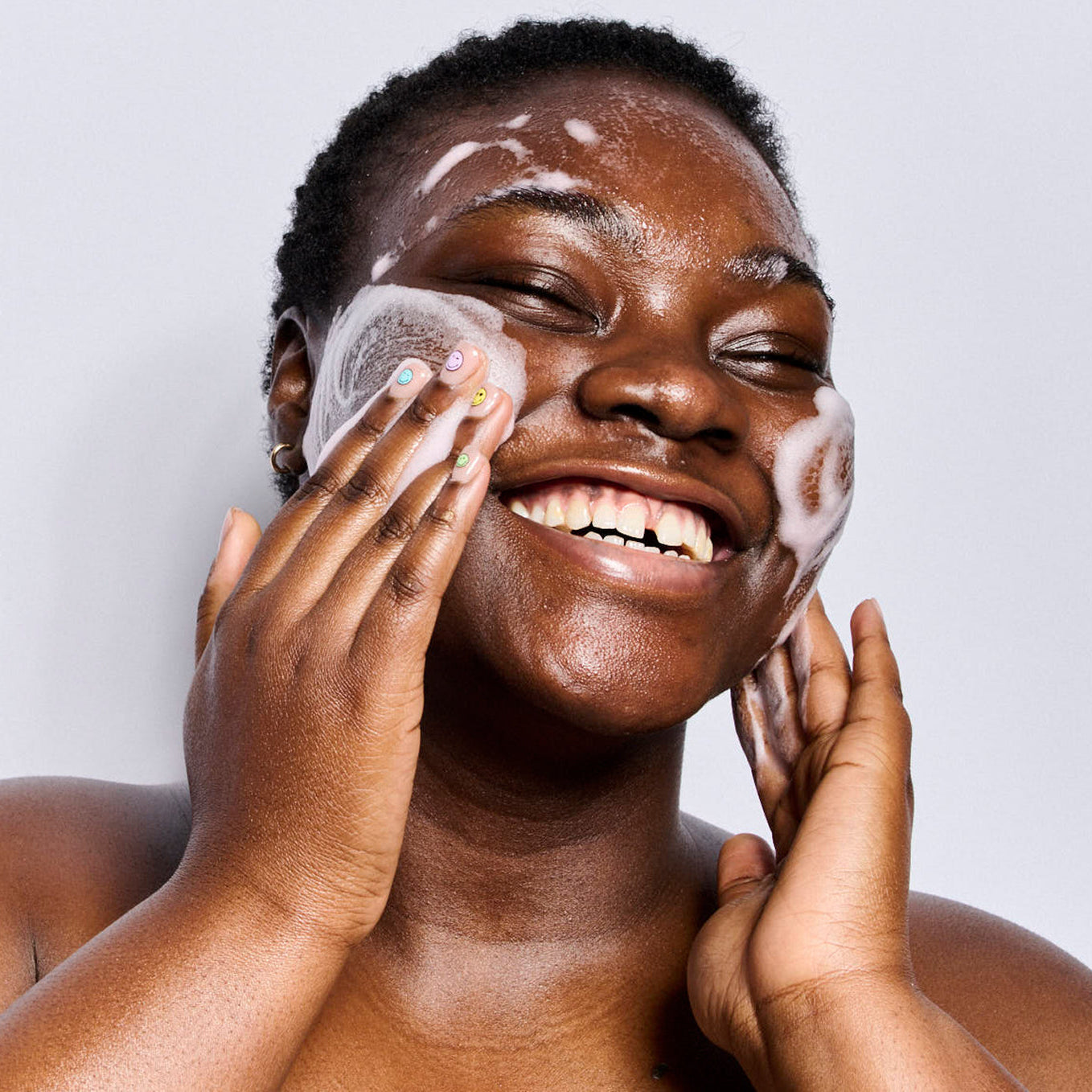 Person applying pink foaming Soft Reset cleanser with a white background