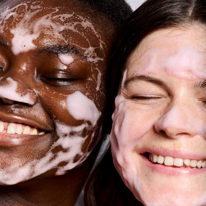 Two people applying pink foaming Soft Reset cleanser with a white background