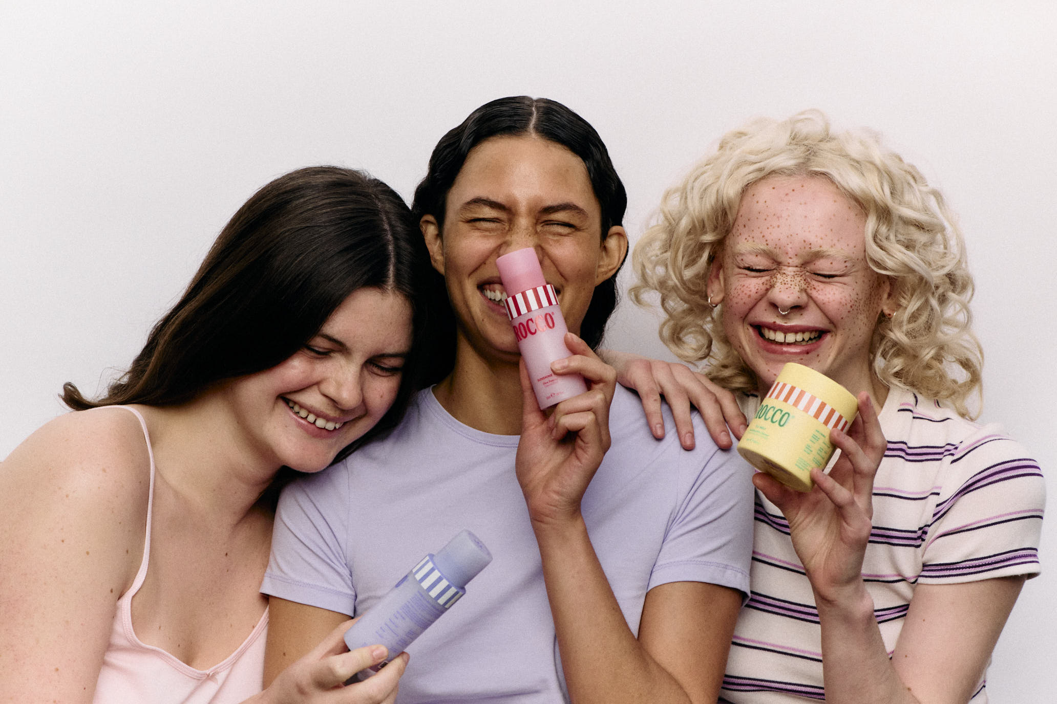 Three people holding colorful bottles against a white background